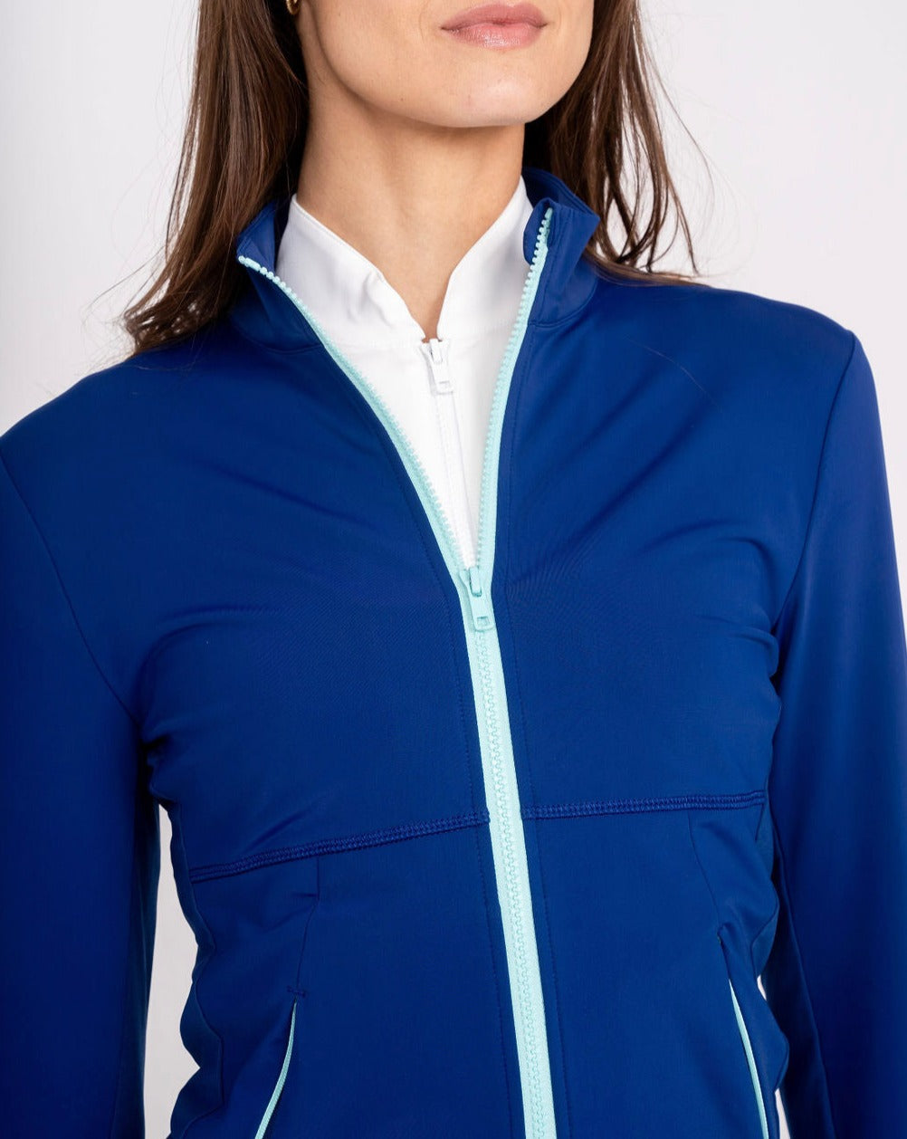 woman wearing a blue jacket over a white shirt on a plain background